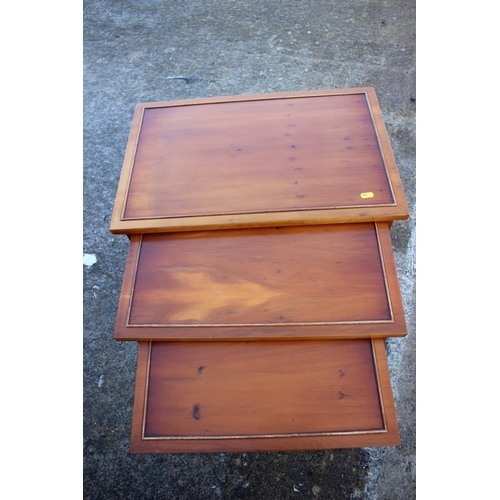 527 - A nest of three yew occasional tables, on turned supports, 23