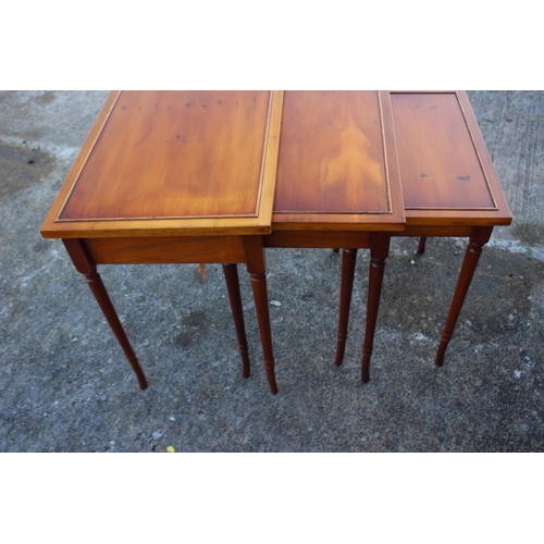 527 - A nest of three yew occasional tables, on turned supports, 23