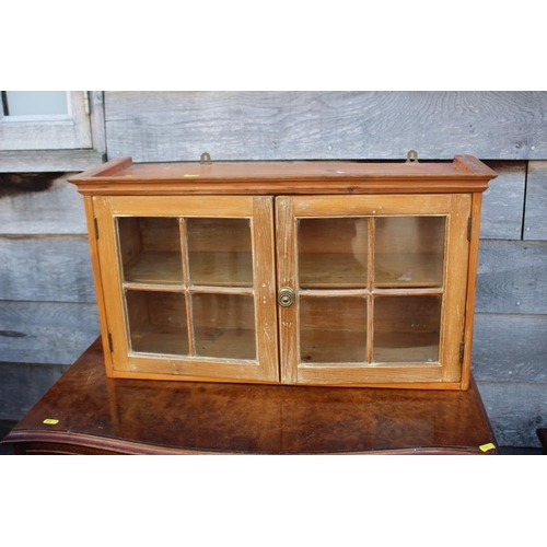 560 - A waxed pine wall hanging cabinet enclosed two glazed panel doors, 27