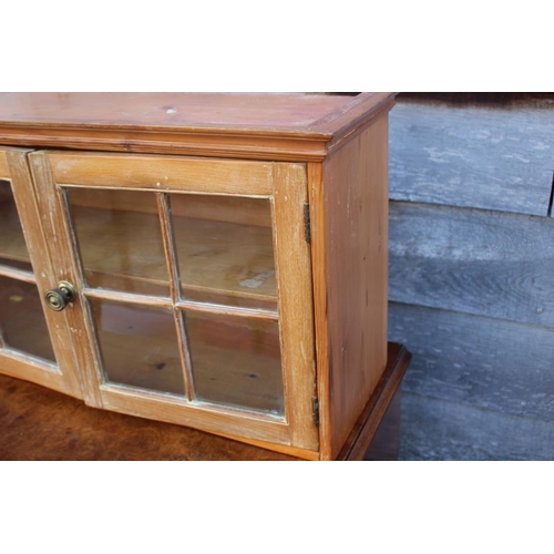 560 - A waxed pine wall hanging cabinet enclosed two glazed panel doors, 27