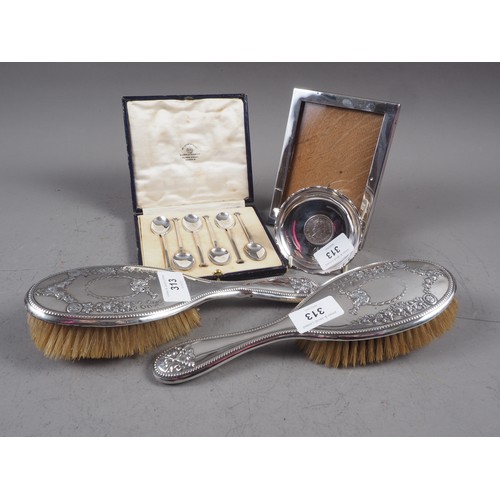 313 - A set of six silver teaspoons, two silver backed brushes, a silver photo frame and a silver dish, in... 