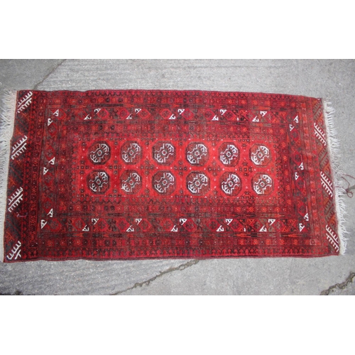 650 - A Bokhara rug of traditional design with twelve central elephant guls on a red ground in shades of b... 