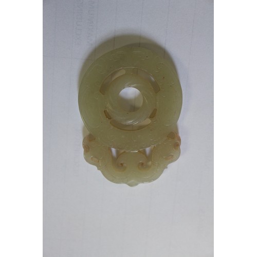 113 - A Chinese green jade roundel with carved and pierced decoration, on stand, 2 3/4