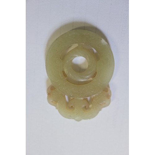 113 - A Chinese green jade roundel with carved and pierced decoration, on stand, 2 3/4