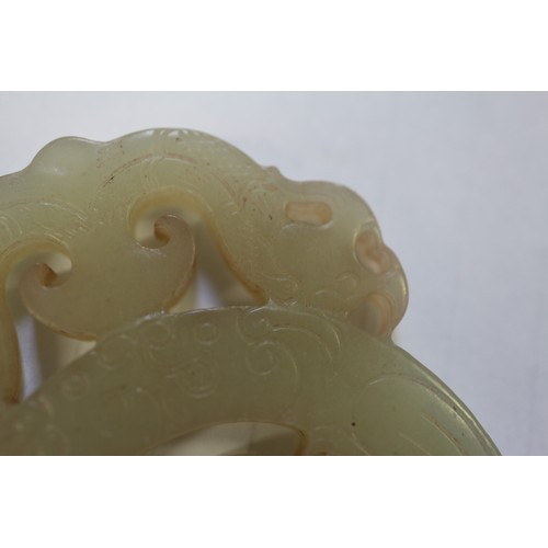 113 - A Chinese green jade roundel with carved and pierced decoration, on stand, 2 3/4