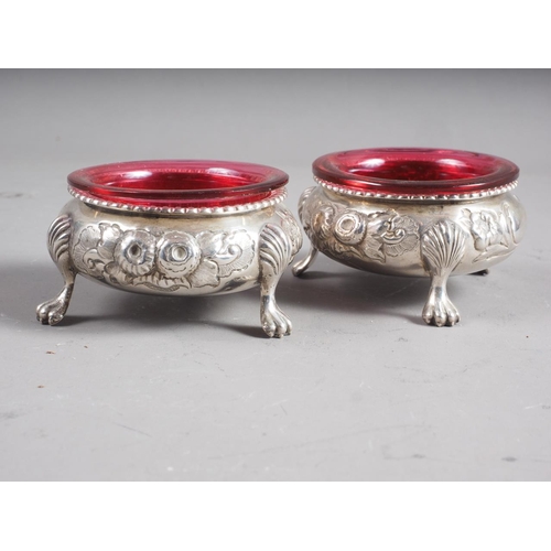 282 - A pair of Victorian silver salt cellars with embossed floral decoration, on paw supports, 4oz troy a... 