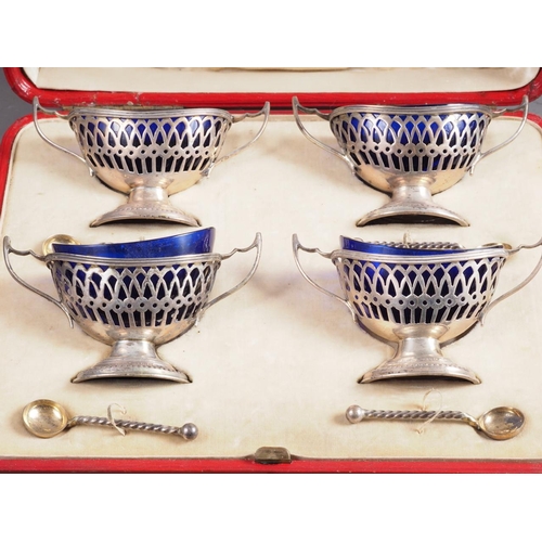 292 - A set of four early 20th century two-handled oval salts with blue glass liners and matched spoons, i... 