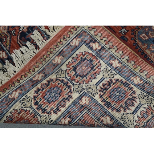 651 - A Louis de Poortere rug of traditional Persian design with geometric design in shades of red, blue, ... 