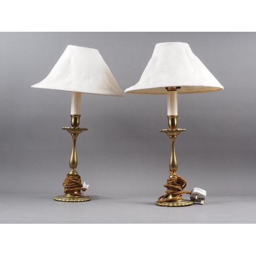 252 - A pair of brass table lamps, on circular shaped bases with Art Nouveau design fabric shades, 19 1/2