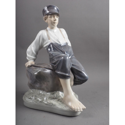 18 - A circa 1960s Royal Copenhagen figure of a shepherd boy sitting on a rock, 12 1/2