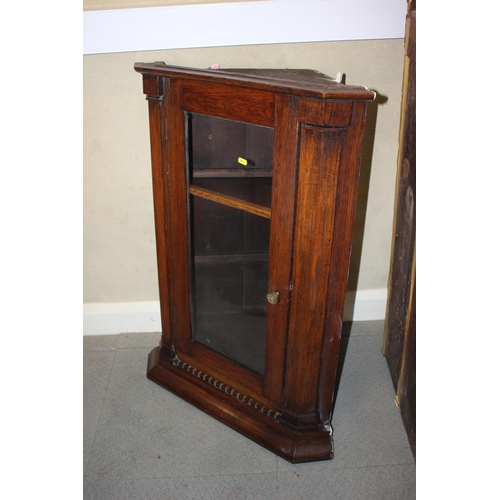 496 - An oak corner cabinet with dentil moulding enclosed glazed panel door, 25 1/2