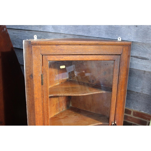 498 - An oak corner hanging cabinet, interior fitted shape shelves enclosed glazed panel door, 23