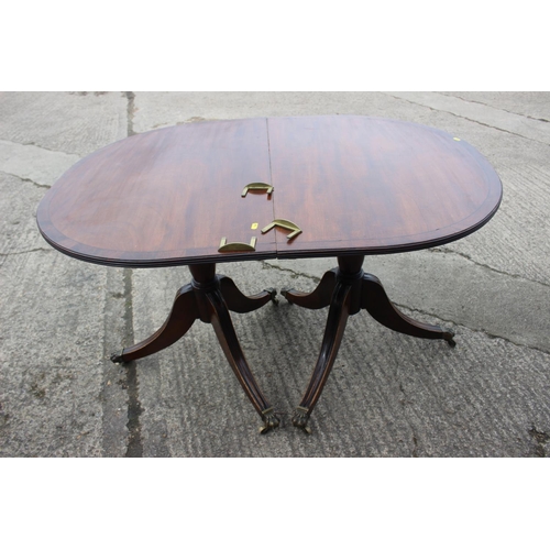 547 - A mahogany and banded double pedestal dining table with two extra leaves, on turned columns and trip... 