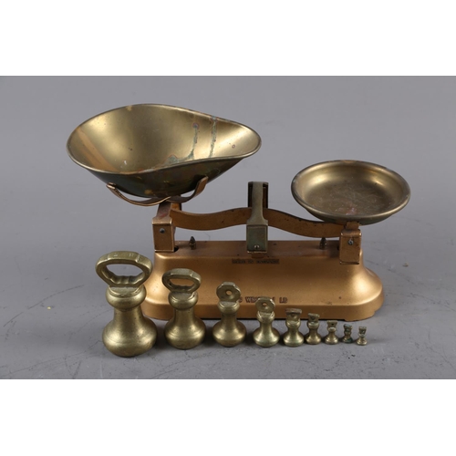 149 - A gilt metal balance and nine brass weights