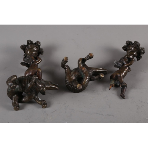 157 - A pair of 19th century bronze candlesticks, formed as putto seated on crocodiles, 8 3/4