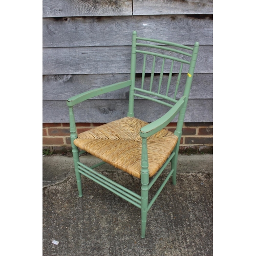 444 - A late 19th century green painted spindle back elbow chair with rush envelope seat