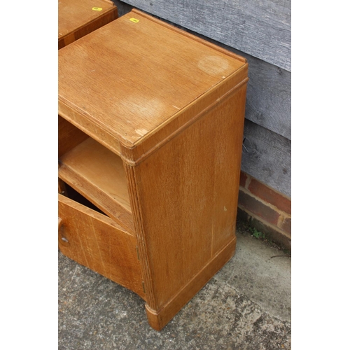 554 - A pair of 1930s light oak bedside cupboards, fitted shelf over one door, on shaped supports, 14