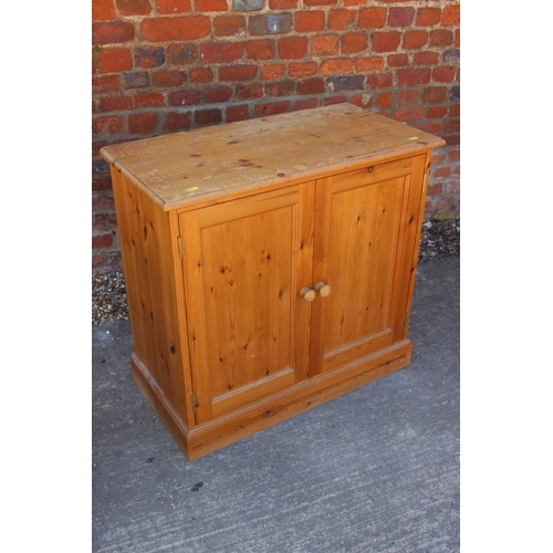 597 - A stripped pine side cabinet, fitted two doors, on block base, 29