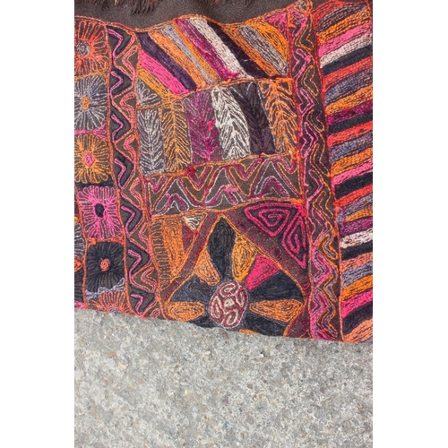 608 - A wool work wall hanging with geometric designs in shades of orange, pink, purple, red, grey and bla... 