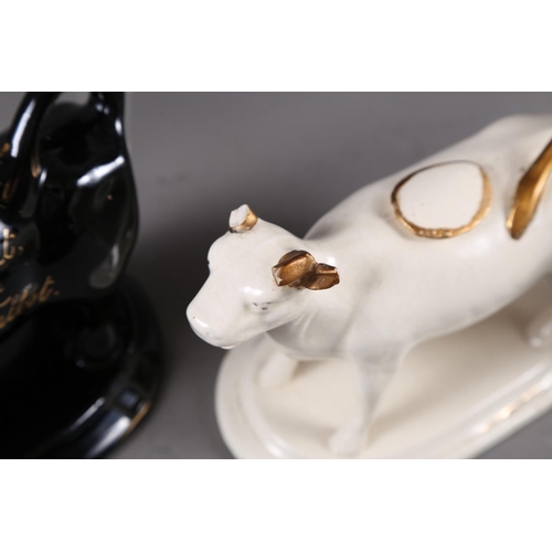 66 - Two black and gilt decorated cow creamers, a white cow creamer and a treacle glazed bull (all with f... 