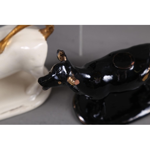 66 - Two black and gilt decorated cow creamers, a white cow creamer and a treacle glazed bull (all with f... 