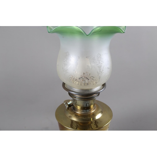 241 - A brass oil lamp with a frosted and green glass shade with engraved decoration, 24