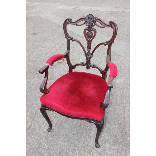 588 - A late 19th century carved walnut open arm chair, upholstered in a red velvet, on cabriole supports