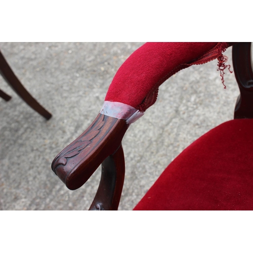 588 - A late 19th century carved walnut open arm chair, upholstered in a red velvet, on cabriole supports