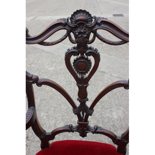 588 - A late 19th century carved walnut open arm chair, upholstered in a red velvet, on cabriole supports