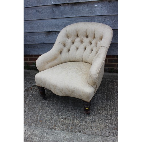 554 - A button backed tub armchair, upholstered in a patterned cream fabric, on castored supports