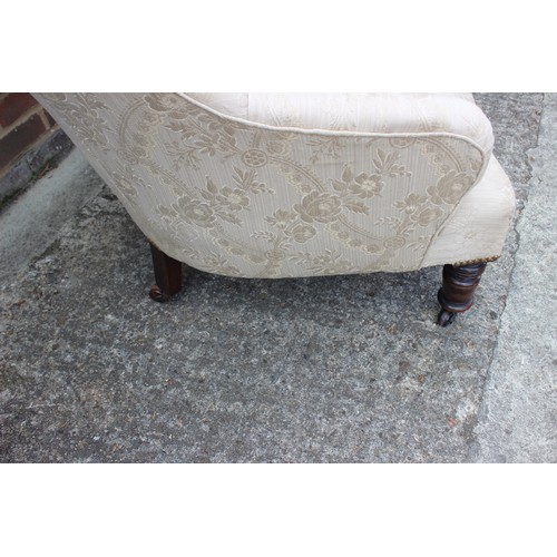 554 - A button backed tub armchair, upholstered in a patterned cream fabric, on castored supports