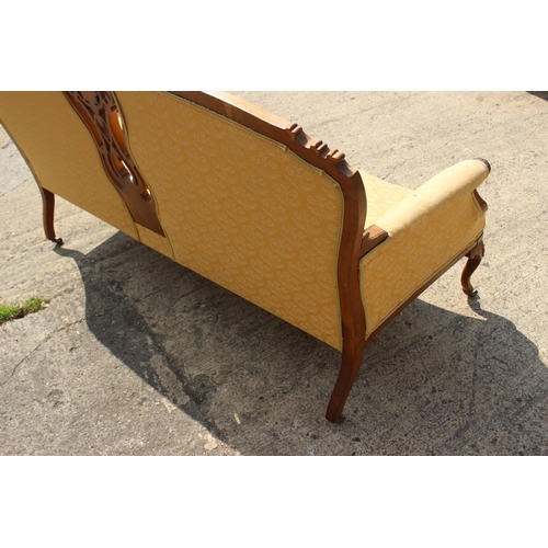 572 - A French walnut showframe settee with carved and pierced central splat, upholstered in a patterned y... 