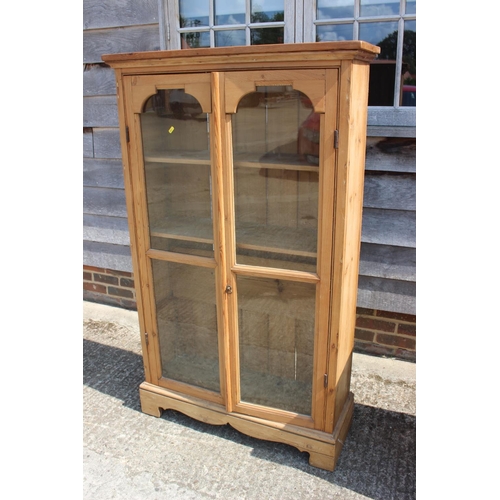 700 - A stripped pine display bookcase enclosed two glazed panel doors, on block base, 36