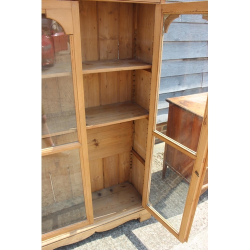 700 - A stripped pine display bookcase enclosed two glazed panel doors, on block base, 36