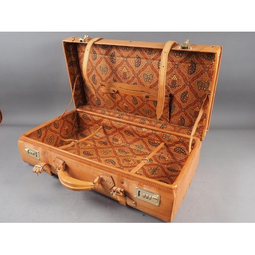 149 - A brown leather and gilt metal mounted overnight bag with paisley fabric interior, 22