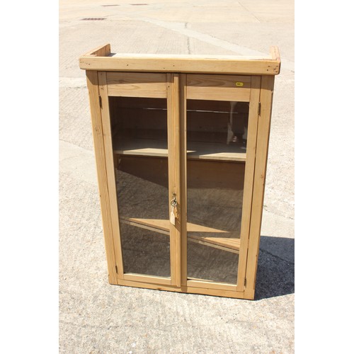 687 - A waxed pine cupboard, fitted three shelves enclosed two glazed doors, 29