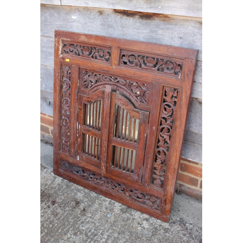 486 - An Indian carved and pierced framed wall mirror enclosed two spindle doors, 36