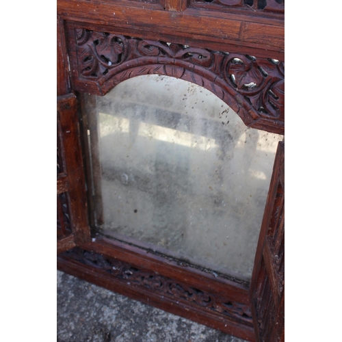 486 - An Indian carved and pierced framed wall mirror enclosed two spindle doors, 36