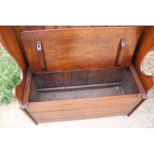 541 - An oak box seat settle with chip carved top rail, on panel end supports, 36