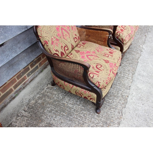 589 - An early 20th century carved mahogany bergere three-piece suite with loose seat cushions, on cabriol... 