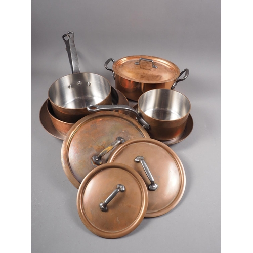 125 - Three copper and iron handled saucepans, two similar frying pans, a tureen and a hanging rack