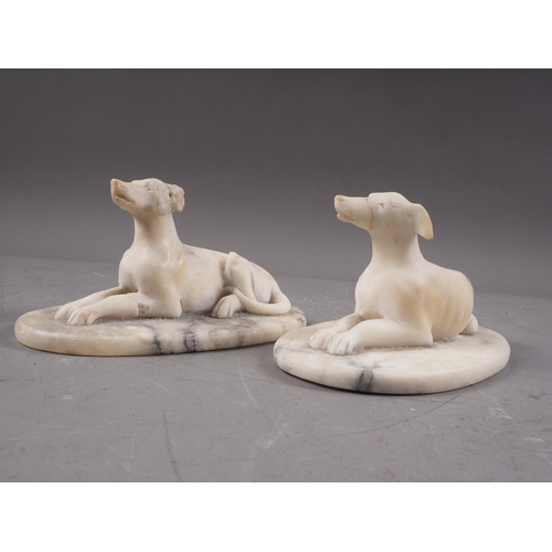 193 - A pair of carved marble reclining greyhounds, on oval bases, 6