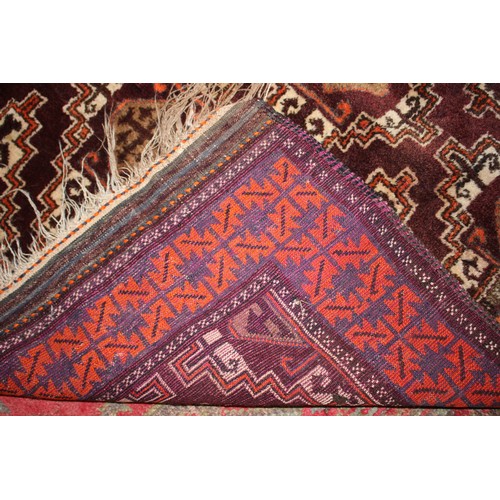 626 - A Kazak style rug with thirteen diamond lozenges on a plum ground on single boarder in shades of ora... 