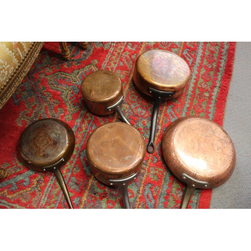 125 - Three copper and iron handled saucepans, two similar frying pans, a tureen and a hanging rack