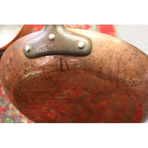 125 - Three copper and iron handled saucepans, two similar frying pans, a tureen and a hanging rack