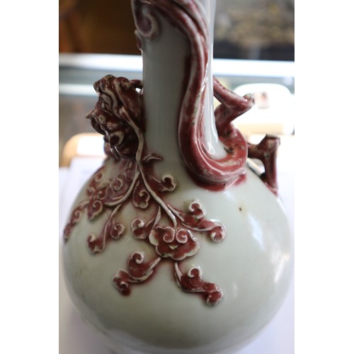 76 - A Chinese pale glazed bottle neck vase with relief iron oxide coloured dragon decoration, 11 3/4