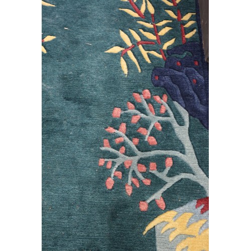 623 - A 1930s style Chinese contour pile rug with stylised bamboo, rocks and prunus tree design on a green... 