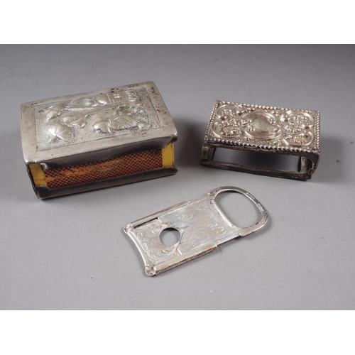 330 - A silver cigar cutter with engraved decoration, a silver matchbox holder, and a similar larger white... 