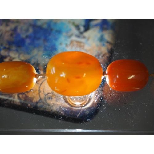 367 - An Art Deco butterscotch/egg yolk amber graduated bead necklace, the largest oval bead 19mm wide, to... 