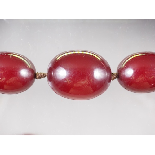 368 - An Art Deco cherry amber Bakelite graduated bead necklace, the largest oval bead 22mm wide, total we... 